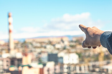 A city with multi-storey residential buildings and a large chimney from the boiler room in the morning under the sun.