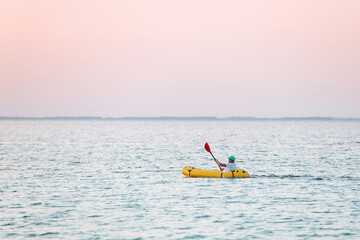 Distant view of man in the yellow colored boat that is in the sea