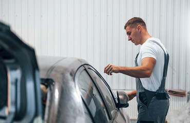 Caucasian automobile repairman in uniform works in garage