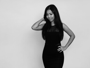 Beautiful asian woman with long black hair posing in dress on grey background