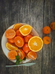 A white plate full of orange slices and tangerines 