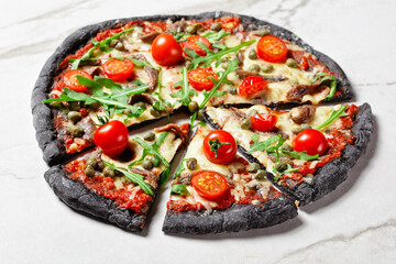 black dough pizza with anchovy arugula, capers