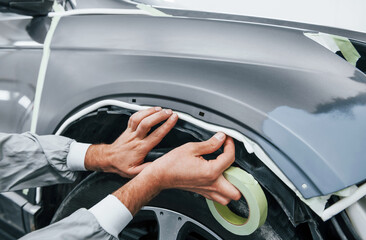Detailed work. Caucasian automobile repairman in uniform have job in garage