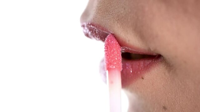Closeup of woman applying a lip gloss on her lips
