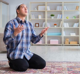 Young muslim man praying at home