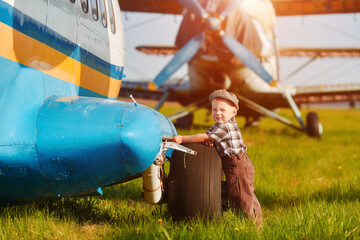 A child stand near an old plane and dreams of becoming a pilot when he grows up. The concept of choosing a future profession