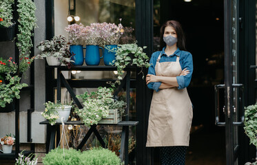Decorative plants, gardening and floristry. Confident lady in apron and protective mask with crossed arms