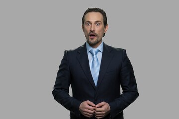 Portrait of shocked businessman on gray background. Amazed handsome businessman with open mouth.