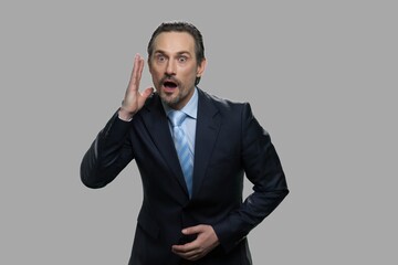 Businessman with shocked facial expression. Amazed scared businessman against gray background.