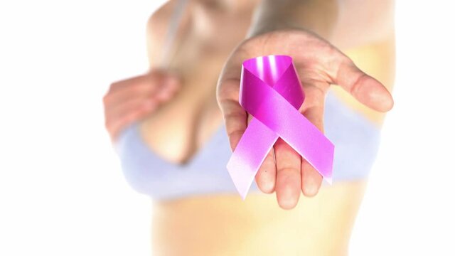 a woman in a bra holds in her hand a pink ribbon on a white background