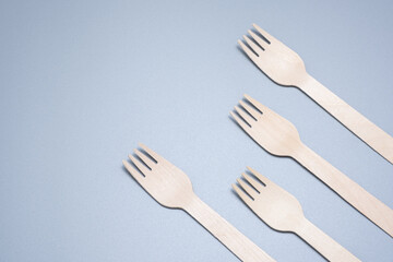Wooden disposable fork on a gray background close-up. Environmentally friendly product.