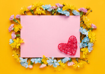 Obraz premium Valentine's day or Wedding romantic concept with flowers and red heart on yellow background. Top view, copy space.