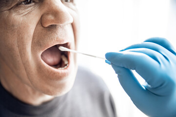 Medical worker wearing protective equipment testing senior old man for dangerous corona virus using...