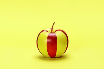 Striped yellow and red apple on a yellow background.