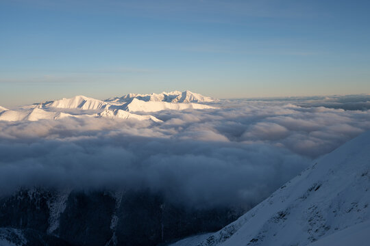 Magnificent and silent view on mountains during sunset. Adventure ascent of alpine peak in snow. Hiking theme. Seasonal natural scene. Mountains above the clouds. Adventure concept