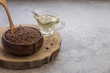 Linseed oil in a glass gravy boat and flaxseed in a wooden bowl vegetable source of omega-3, lowers cholesterol, used in food as a dietary salad dressing, in cosmetology, in herbal medicine