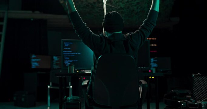 Hooded Hacker Using His Computer with Different Information to Break into Corporate Data Servers and Infects them with Virus. His Hideout Place has Dark Atmosphere. It stretches when hacked