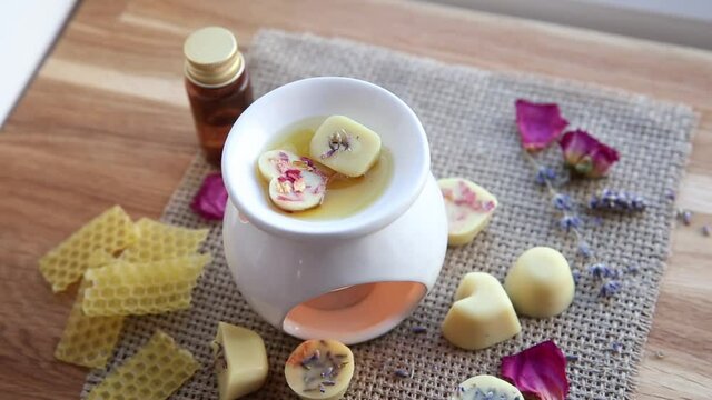 Using homemade mini wax melts in aromatherapy lamp diffuser at home interior concept. Melts making ingredients on table for unbleached beeswax, solid coconut oil, essential oil, dried flowers.