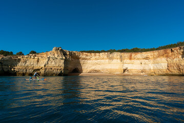 Fototapeta na wymiar father and twho young children paddle on a SUP board along the Algarve coast in Portugal
