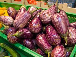 Striped graffiti eggplant in a box on the market. A lot of purple vegetables with white longitudinal stripes.