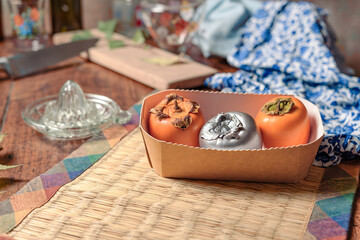 Silver and natural persimmons and kitchen tools, on a wooden table.