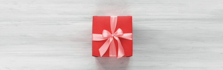 red box tied with a gold ribbon. the ribbon is tied on a box in the form of a beautiful bow. holiday gift concept