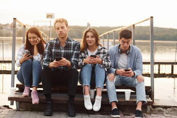 Near the lake. Group of young cheerful friends that is outdoors having fun together