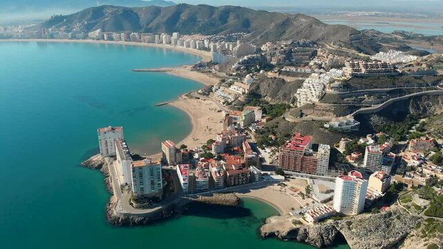 Aerial drone point of view Cullera sandy empty beach and townscape rooftops during sunny winter day. Touristic famous place. Province of Alicante, Costa Blanca, Spain