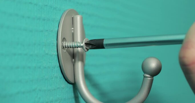 Drving screw into wall plug for installing a coat hanger hook for home improvement