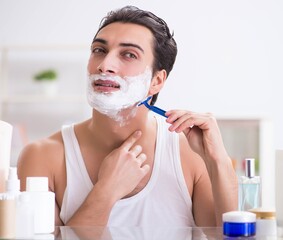 Young handsome man shaving early in the morning at home