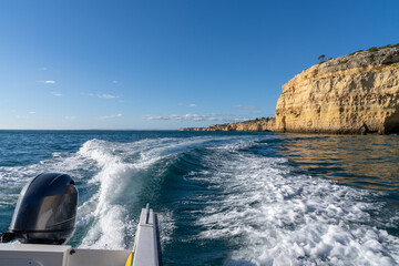 outboard motor of a speeding coast with ocean and rocky coast behind