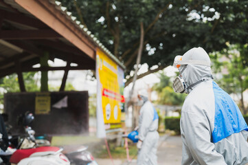 Fototapeta premium Disinfecting of office to prevent COVID-19, person in white hazmat suit with disinfect Cleaning and sterilizing the not crowded city streets.