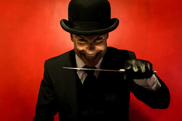 Portrait of Man in Dark Suit and Bowler Hat Holding Sharp Knife. Crazy Killer with Weapon. Maniacal Grin. Comic Book Henchman.