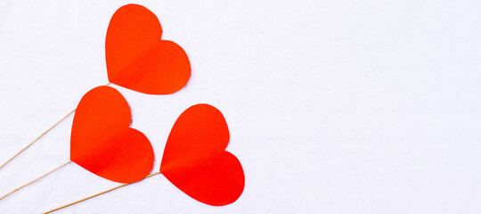 Banner-long format. Textile white plush background with red hearts on wooden sticks. Empty space for your advertisement.