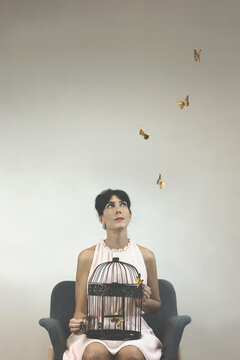 conceptual photo of freedom with a  woman releasing colorful art butterflies from a cage