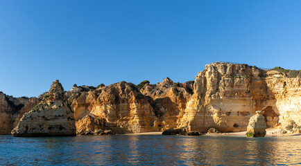the beaches and cliifs of the Algarve Coast in Portugal under bright blue sky