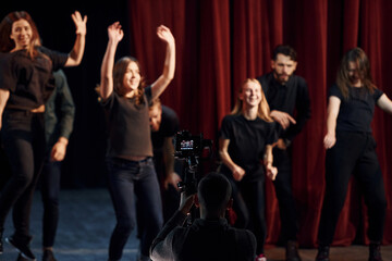 Happy people celebrating success. Group of actors in dark colored clothes on rehearsal in the...