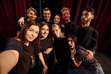 Making selfie. Group of actors in dark colored clothes on rehearsal in the theater
