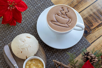 Vista superior de una taza de chocolate y pan con mermelada sobre una mesa.