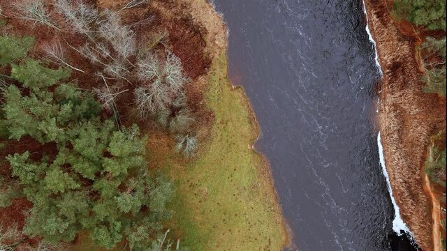 Red sandstone cliffs in the banks of river Salaca during late autumn time, Latvia. Real time drone footage