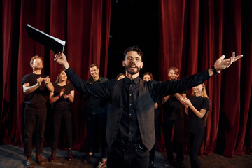 Fototapeta premium Man is practicing his role. Group of actors in dark colored clothes on rehearsal in the theater