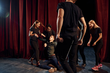 Fight scene. Group of actors in dark colored clothes on rehearsal in the theater