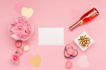 Flowers, bottle of wine, sweets and gift on pink background. Valentines day concept. Flat lay, top view, copy space.