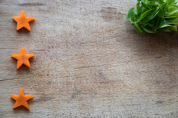raw carrot cut in a star shape on a wooden board, with top view and space to write text or recipes.