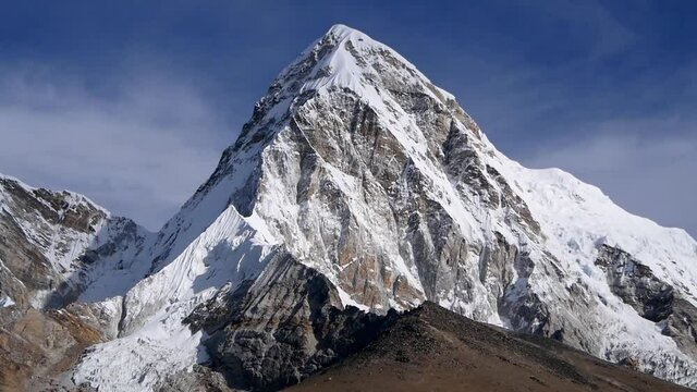Front view of majestic snow-capped mountain Pumori (summit: 7,161m) with peak of Kala Patthar below in the rugged Himalayas with clouds passing by slowly viewed fron Lobuche, Khumbu, Nepal.