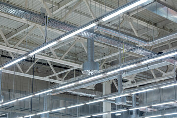 Lamps with diode lighting and ventilation under the ceiling of a modern warehouse or shopping center. Ceiling air conditioning of the stadium or exhibition hall roof.