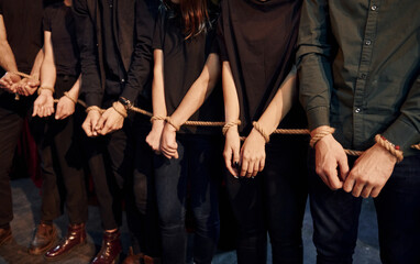 Fototapeta na wymiar With rope in hands. Group of actors in dark colored clothes on rehearsal in the theater