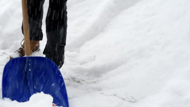 un uomo mentre pulisce la strada dalla neve con un badile durante una grande nevicata