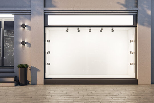 Luxury boutique with blank glass storefront and backlight lamps.