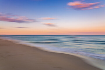 Naklejka na ściany i meble Palm Beach Island beach sunset with slow shutter pan of pink, blue and purple skies with green ocean water